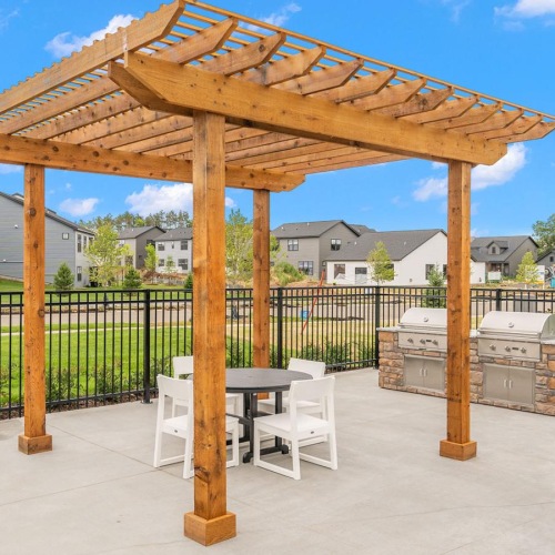 a wooden gazebo with a table and chairs in front of a fence